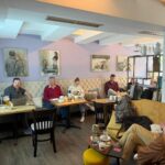 Weitwinkelaufnahme der teilnehmenden Unternehmer beim Netzwerktreffen und KI-Workshop des BDS Fürstenfeldbruck in gemütlicher Café-Atmosphäre.