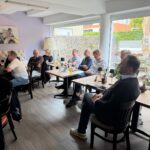 Aufmerksame Unternehmer und Selbständige aus Fürstenfeldbruck sitzen im Café und lauschen dem Vortrag beim ersten KI-Café des BDS.