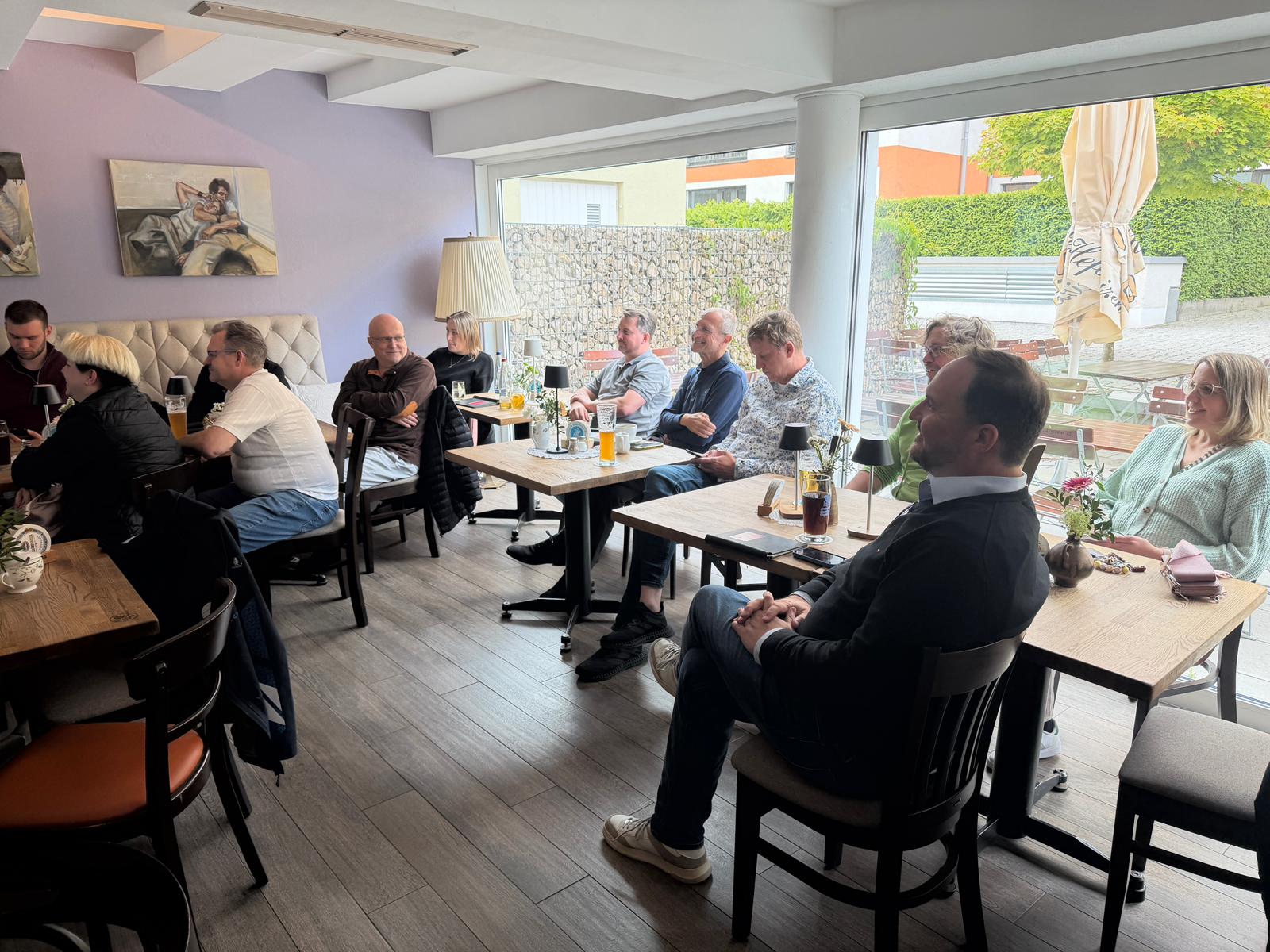 Aufmerksame Unternehmer und Selbständige aus Fürstenfeldbruck sitzen im Café und lauschen dem Vortrag beim ersten KI-Café des BDS.